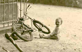Im Sand sitzend vor liegendem Fahrrad